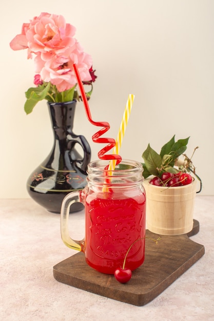 Vista frontal de un cóctel de cereza roja con pajitas y cerezas en el escritorio rosa jugo de bebida de frutas de color