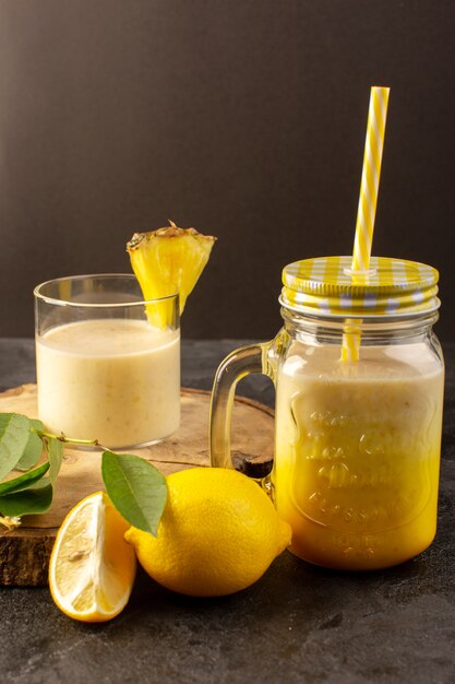 Una vista frontal cóctel fresco deliciosa bebida refrescante dentro puede con paja cerca del escritorio de madera junto con hojas verdes sobre el fondo oscuro beber jugo de verano