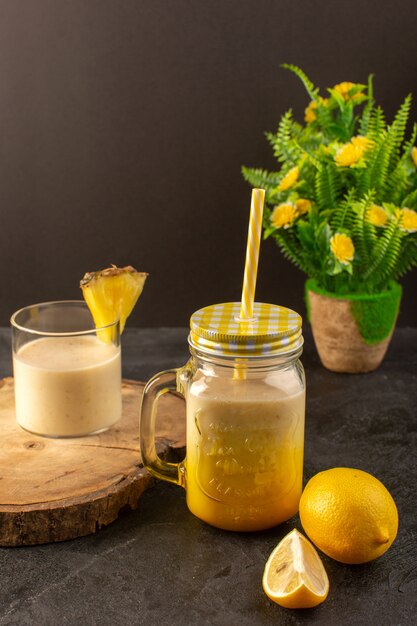 Una vista frontal cóctel fresco deliciosa bebida refrescante dentro puede con paja cerca del escritorio de madera junto con limones en el fondo oscuro beber jugo de verano