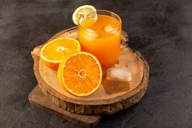 Una vista frontal cóctel frío coloreado dentro de vidrio con cubitos de hielo naranjas aisladas en la oscuridad