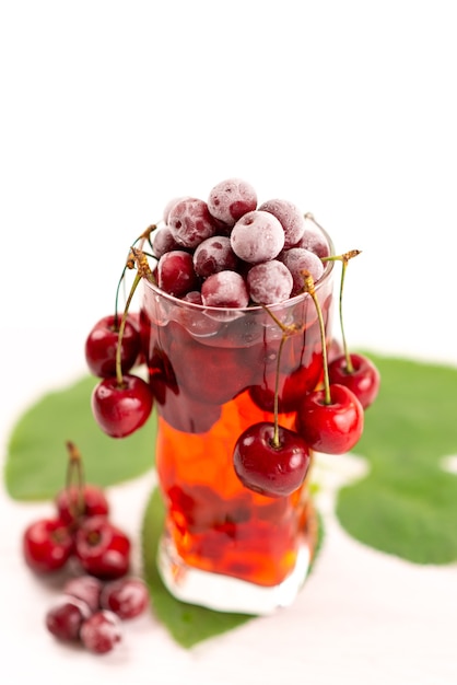Vista frontal de un cóctel de frutas frescas con cerezas rojas frescas de enfriamiento con hielo en blanco, cóctel de jugo de bebida color de fruta