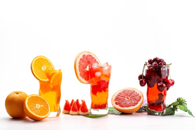 Una vista frontal de cócteles de frutas frescas con rodajas de fruta fresca enfriamiento con hielo en blanco, cóctel de jugo de bebida color de fruta