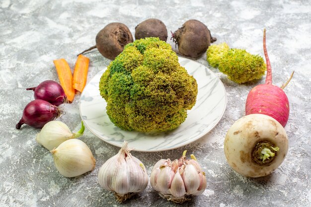 Vista frontal de coliflor fresca con remolacha rábano ajo y cebolla sobre superficie blanca