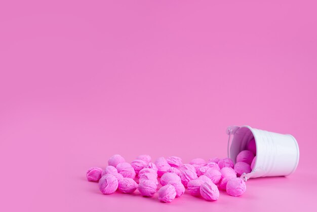 Una vista frontal de color rosa, caramelos dentro y fuera de blanco, canasta en rosa, dulces de color caramelo