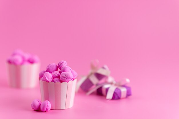 Una vista frontal de color rosa, caramelos junto con cajas de regalo de color púrpura en rosa, dulce de azúcar color caramelo