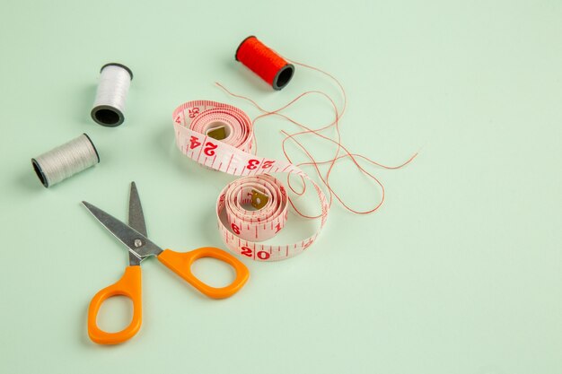 Vista frontal de color rosa centímetro con tijeras sobre una superficie verde agujas de color coser foto pin de ropa coser
