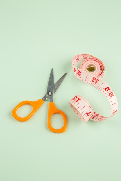 Vista frontal de color rosa centímetro con tijeras en la superficie verde foto de coser pin de ropa coser color