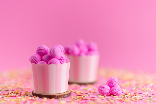 Una vista frontal de color rosa, galletas deliciosas y deliciosas junto con caramelos de colores en rosa, galleta de galleta de azúcar dulce