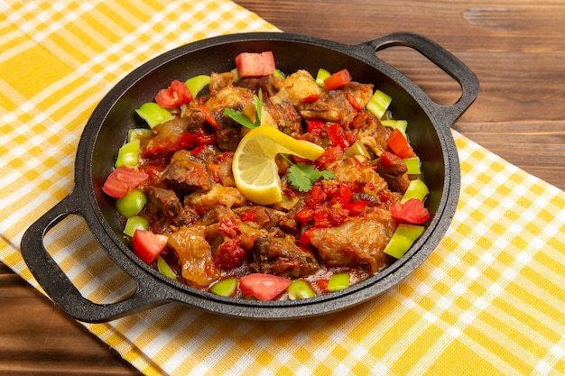 Vista frontal de comida vegetal cocida con carne y pimientos en rodajas en el escritorio de madera marrón