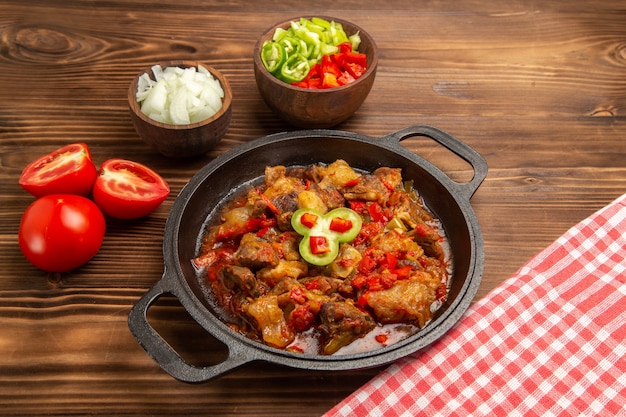 Vista frontal de comida vegetal cocida con ensalada de pimiento en rodajas sobre superficie marrón