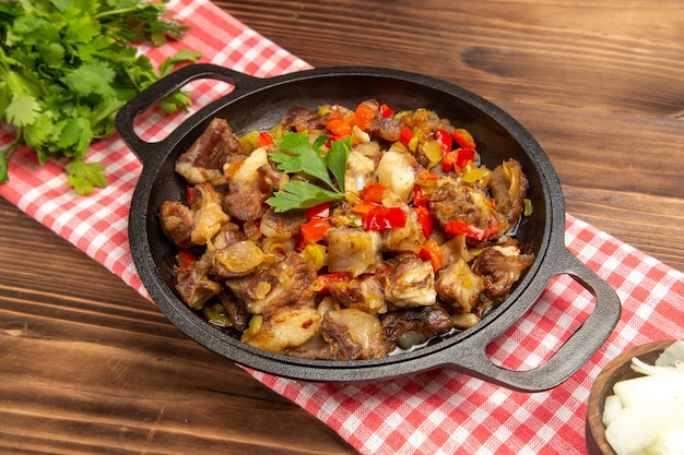 Vista frontal de la comida de verduras cocidas, incluidas las verduras y la carne dentro de un escritorio de madera marrón