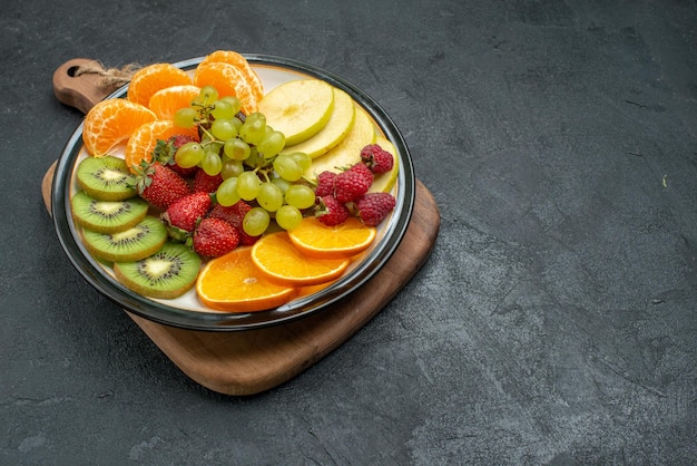 Vista frontal de la composición de diferentes frutas frescas en rodajas y maduras sobre el fondo gris suaves frutas frescas salud madura