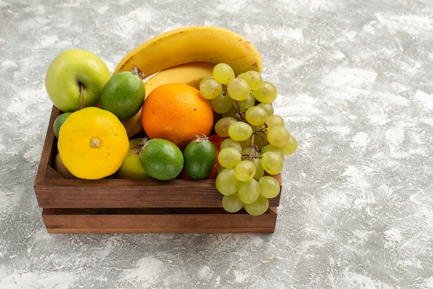 Vista frontal de la composición de frutas frescas, plátanos, uvas y feijoa sobre un fondo blanco, fruta suave vitamina salud fresca