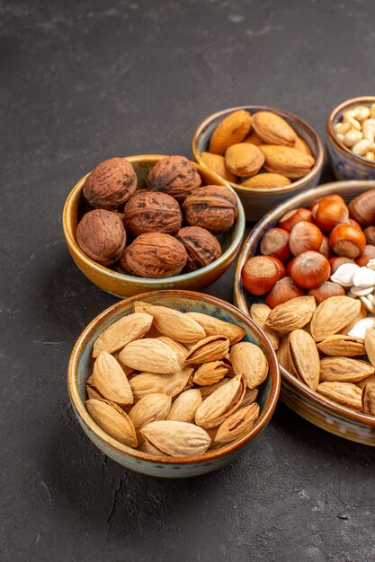 Vista frontal de la composición de nueces cacahuetes y otras nueces sobre superficie oscura