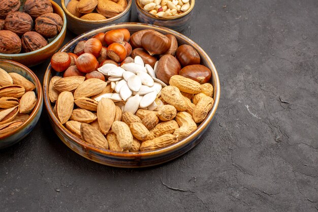 Vista frontal de la composición de nueces cacahuetes y otras nueces sobre superficie oscura