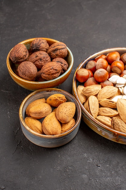 Vista frontal de la composición de nueces cacahuetes y otras nueces en superficie gris