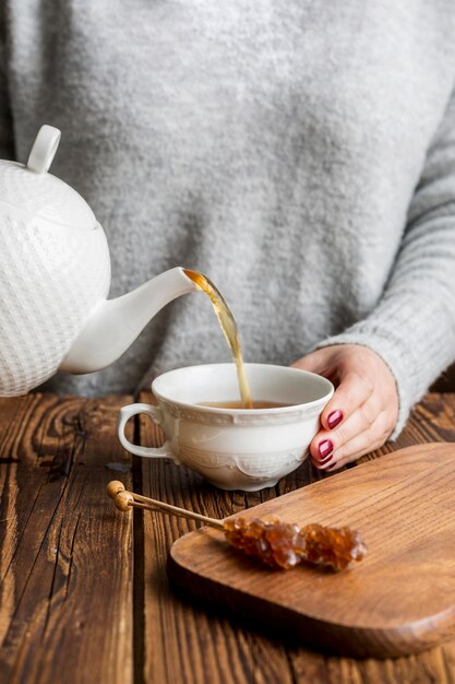 Vista frontal del concepto de té vertiendo mujer