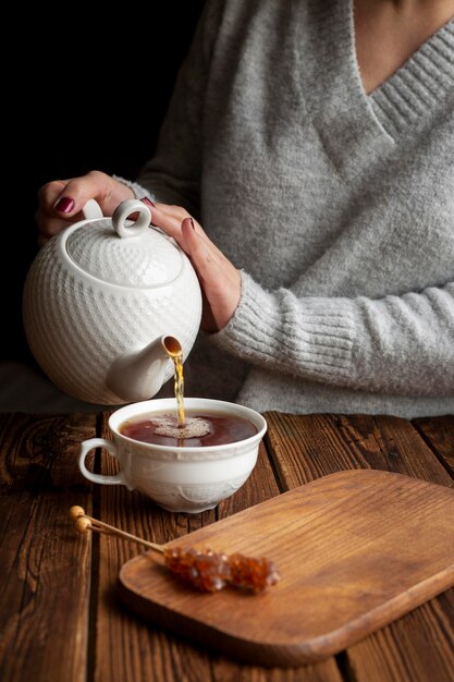 Vista frontal del concepto de té vertiendo mujer