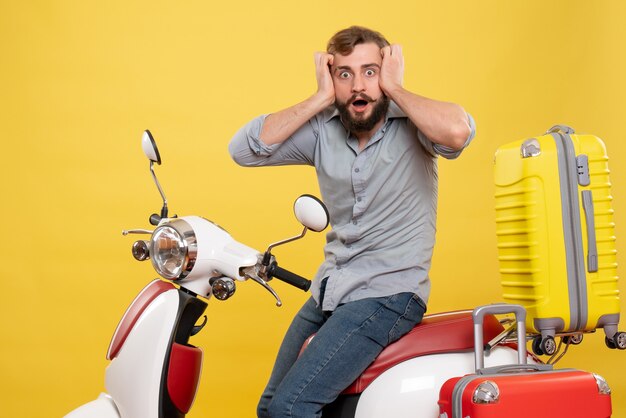 Vista frontal del concepto de viaje con joven barbudo asustado sentado en moto en amarillo