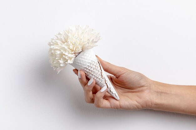 Vista frontal del cono de helado de mano con flor