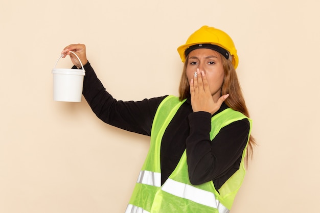 Vista frontal del constructor femenino en casco amarillo camisa negra con pintura bostezando en el escritorio blanco arquitecto constructor femenino