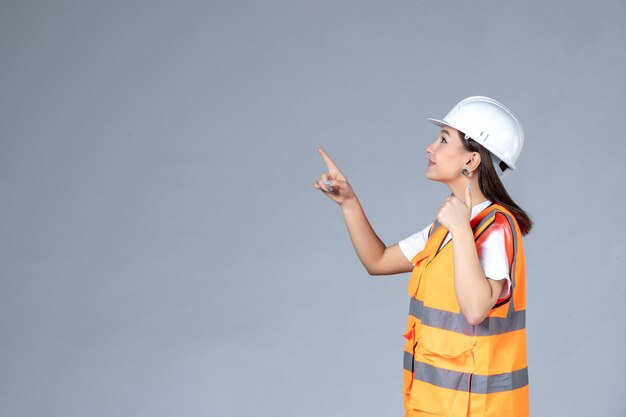 Vista frontal del constructor femenino en uniforme en la pared blanca