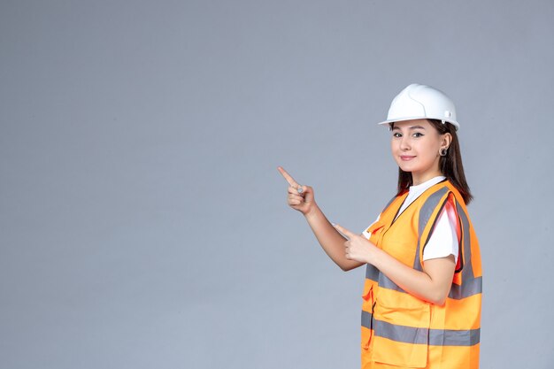 Vista frontal del constructor femenino en uniforme en la pared blanca