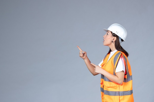 Vista frontal del constructor femenino en uniforme en la pared blanca