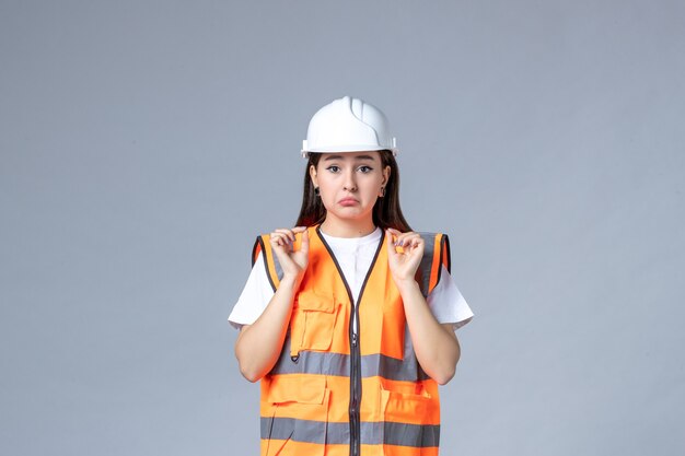 Vista frontal del constructor femenino en uniforme en la pared blanca