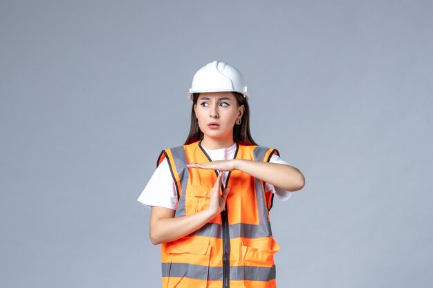 Vista frontal del constructor femenino en uniforme en la pared blanca