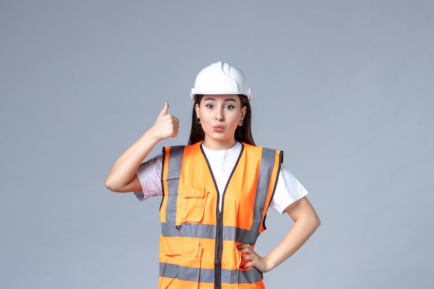 Vista frontal del constructor femenino en uniforme en la pared blanca