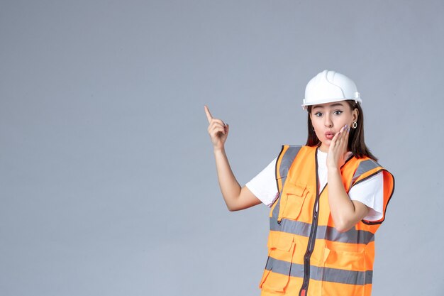 Vista frontal del constructor femenino en uniforme en la pared blanca