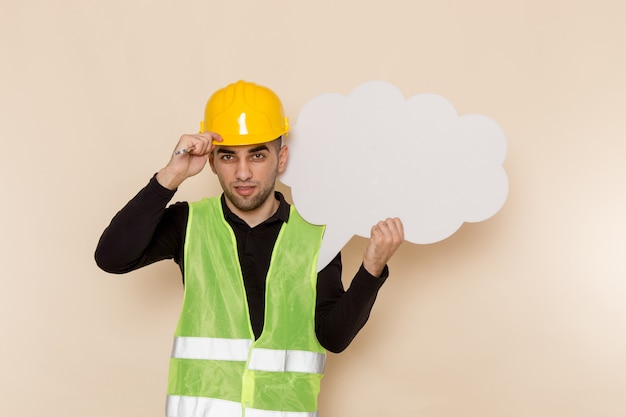 Vista frontal del constructor masculino en casco amarillo con cartel blanco sobre fondo claro