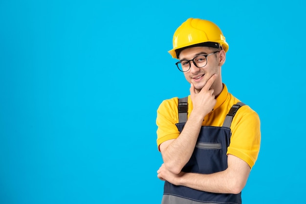 Vista frontal del constructor masculino posando en uniforme y casco en azul