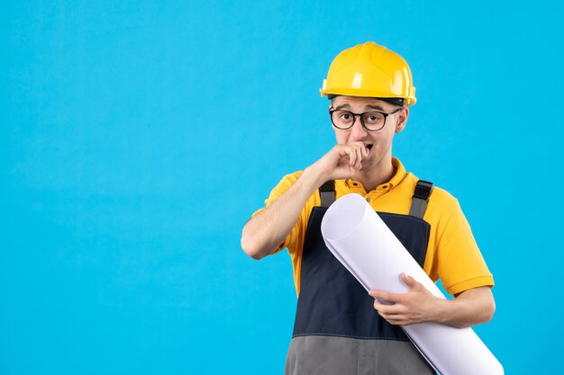 Vista frontal del constructor masculino en uniforme amarillo con plan en azul