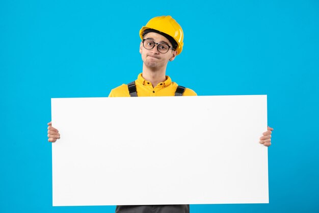 Vista frontal del constructor masculino en uniforme amarillo sobre azul