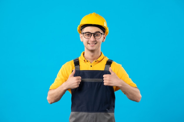 Foto gratuita vista frontal del constructor masculino en uniforme amarillo sobre pared azul