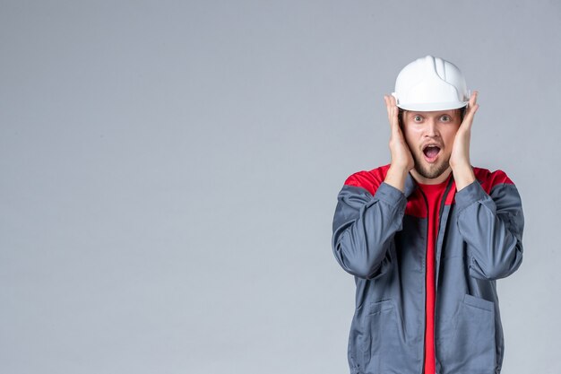 Foto gratuita vista frontal del constructor masculino en uniforme y casco sobre fondo claro