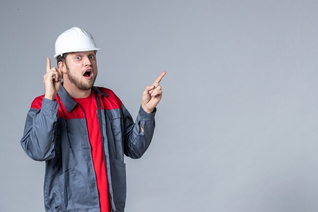 Vista frontal del constructor masculino en uniforme y casco sobre fondo claro