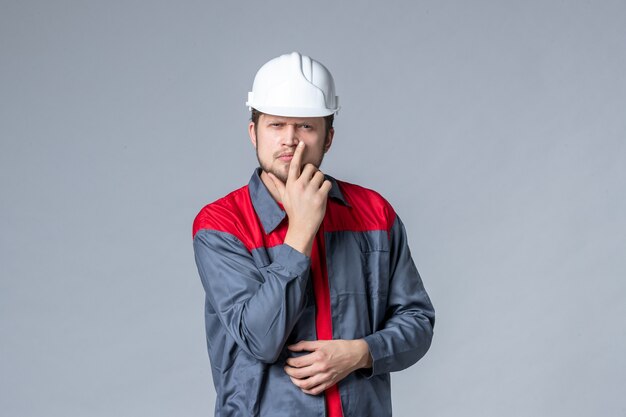 Vista frontal del constructor masculino en uniforme y casco sobre fondo gris