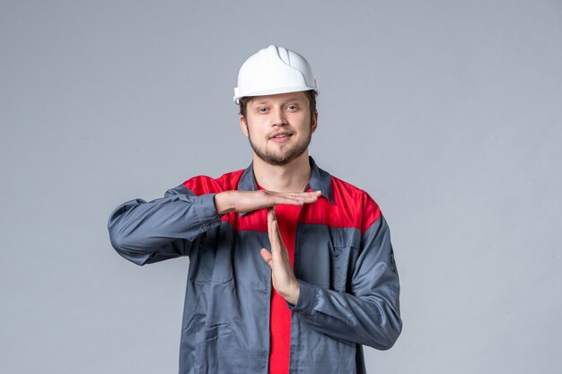 Vista frontal del constructor masculino en uniforme y casco sobre fondo gris