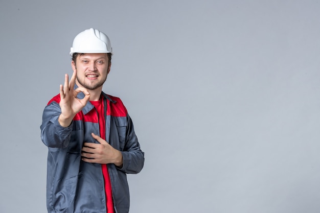 Vista frontal constructor masculino en uniforme con rostro encantado sobre fondo claro