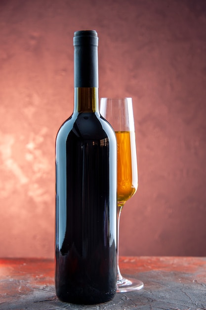 Vista frontal de una copa de champán con una botella en la fiesta de celebración ligera beber alcohol foto color año nuevo