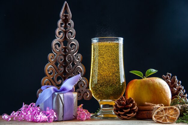 Vista frontal copa de champán con conos de manzana y regalos en fiesta de bebida de color oscuro