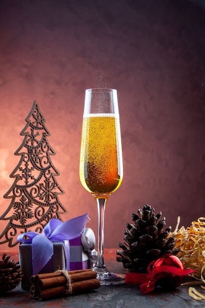 Vista frontal de una copa de champán con regalos y juguetes en una bebida ligera, alcohol, color, champán, año nuevo