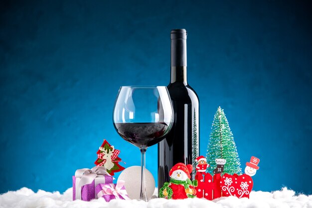Vista frontal de la copa de vino y detalles de Navidad de botella sobre fondo azul.