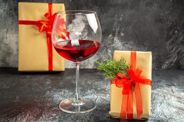 Vista frontal copa de vino regalos de navidad en la oscuridad