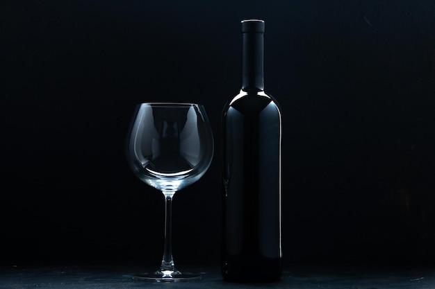 Vista frontal copa de vino vacía con botella de vino sobre fondo oscuro color vino alcohol celebración restaurante de vacaciones
