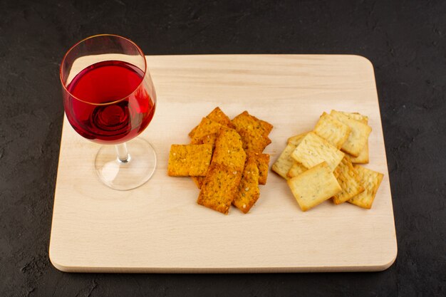 Una vista frontal de copas de vino junto con diferentes patatas fritas en un escritorio de madera