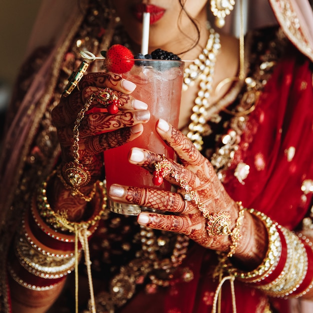 Vista frontal de la cosecha de la novia india es drinkinkg cocktail en vestimenta tradicional